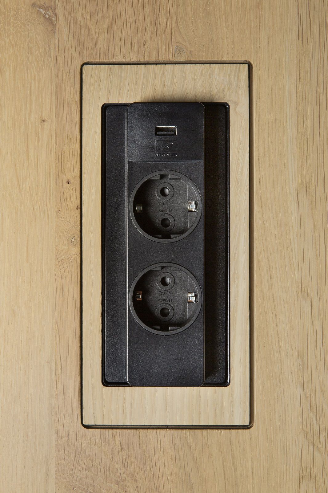 Detailaufnahme: Integrierte Steckdosenleiste mit USB-Anschluss im Ethnicraft Bok Cowork Schreibtisch für modernes Homeoffice.