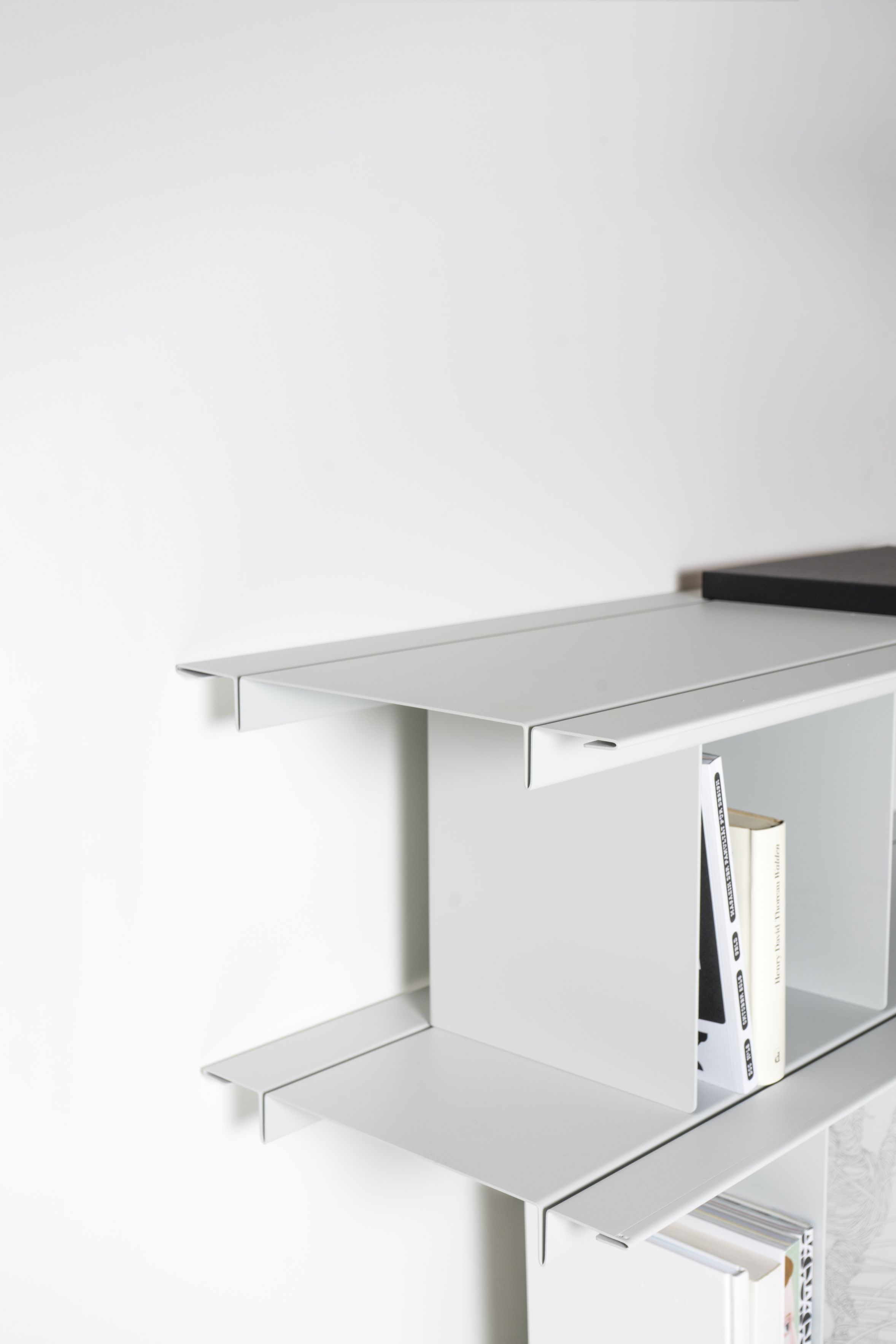 Detailaufnahme des Zoll D Regals von Nils Holger Moormann, ein minimalistisches, weißes Wandregal mit Büchern.