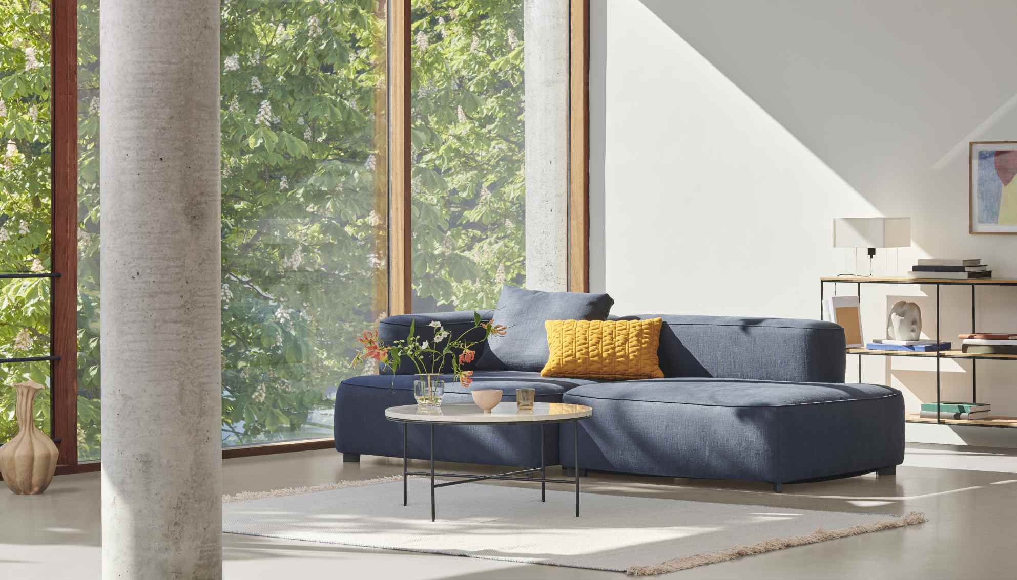 Moderner Wohnraum mit blauem Sofa, Fritz Hansen Couchtisch Planner und minimalistischem Design.