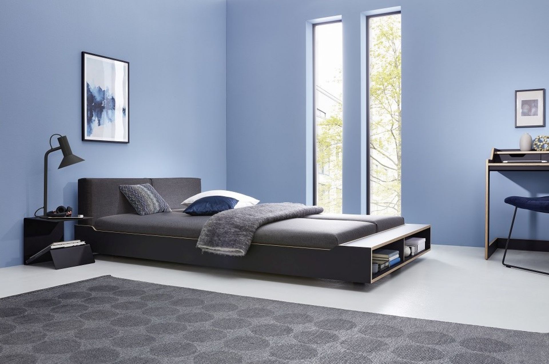 Modernes graues Polsterbett mit Stauraum im Schlafzimmer mit blauen Wänden und Teppich.