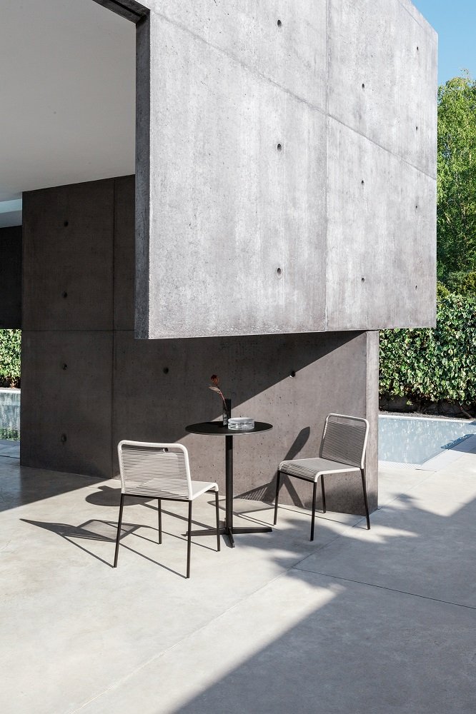 ARIA S42 Outdoor Chair von La Palma mit Tisch auf einer Terrasse vor Betonwand.