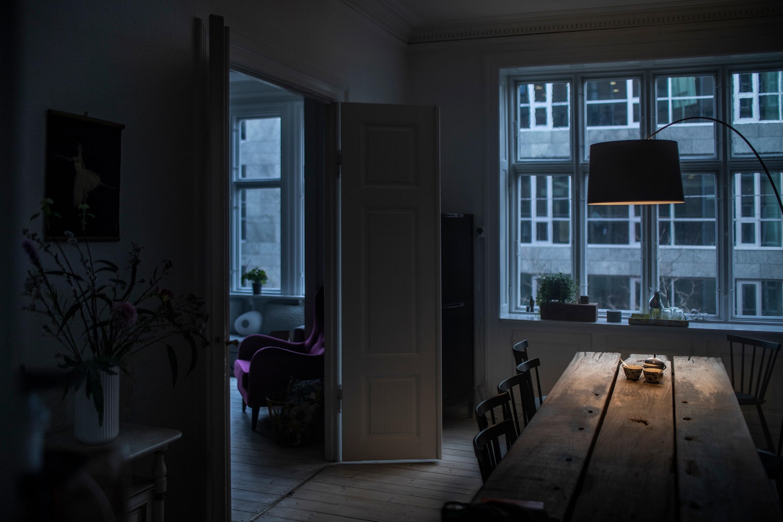 Twiggy Stehleuchte von Foscarini beleuchtet dunkles Esszimmer mit Holztisch und Fensterfront im Hintergrund.