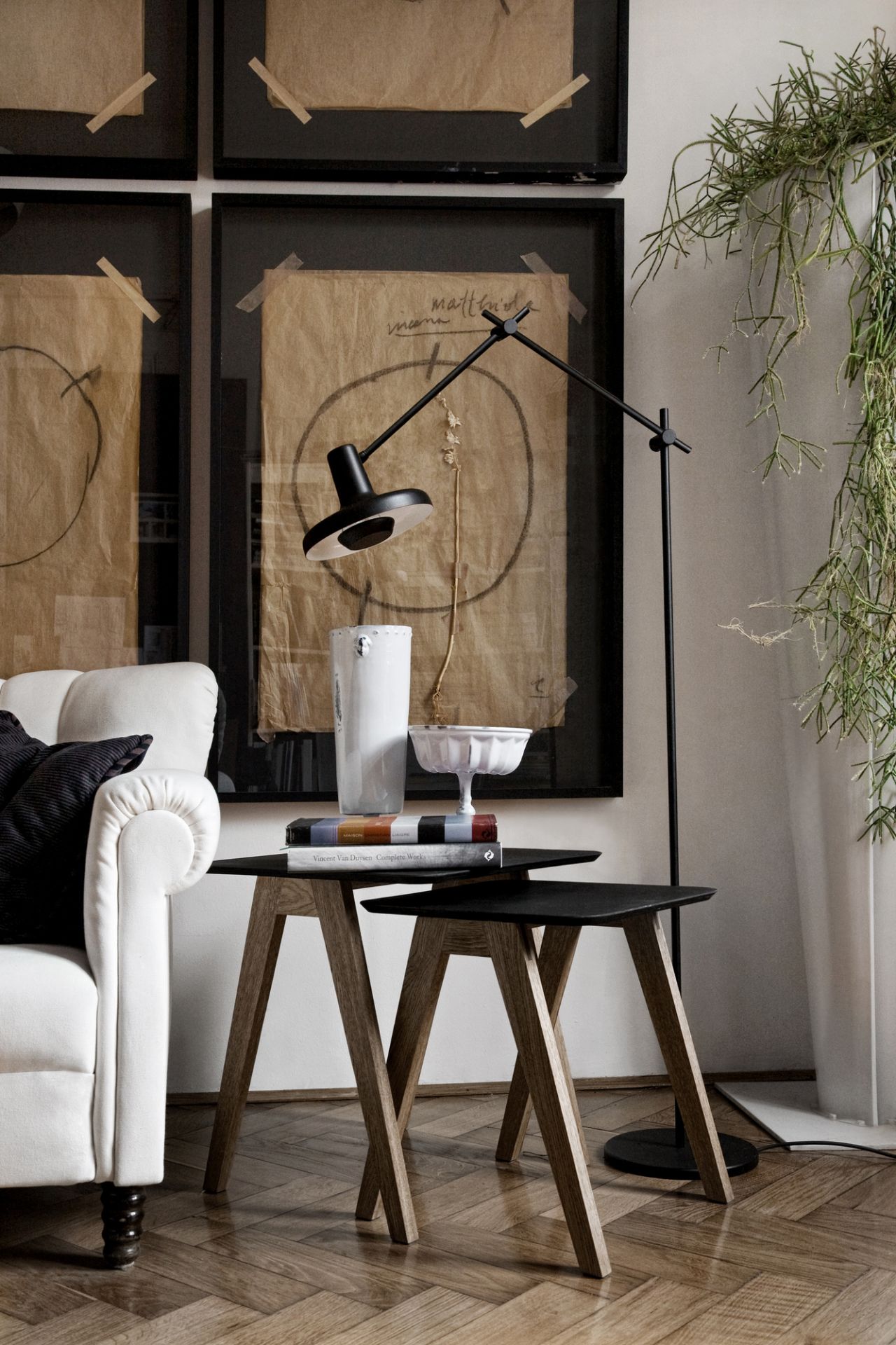 Schwarze Stehleuchte neben Couchtisch mit Deko-Objekten und Büchern, moderne Innenarchitektur für Wohnzimmer und Leseecke.