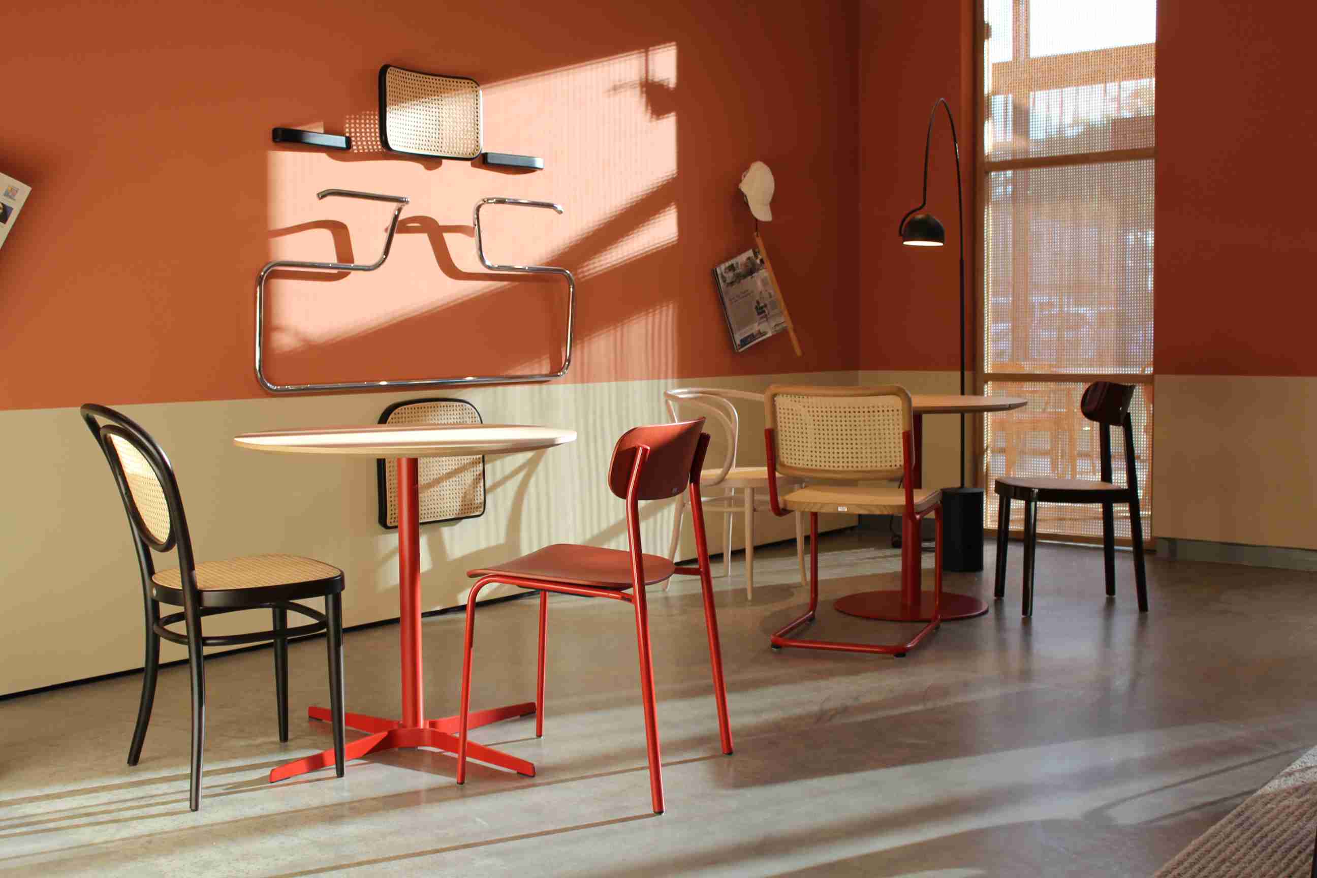 Innenaufnahme mit Thonet Stahlrohrstühlen S 243 in Olivgrün und anderen Farben um Tischen arrangiert.