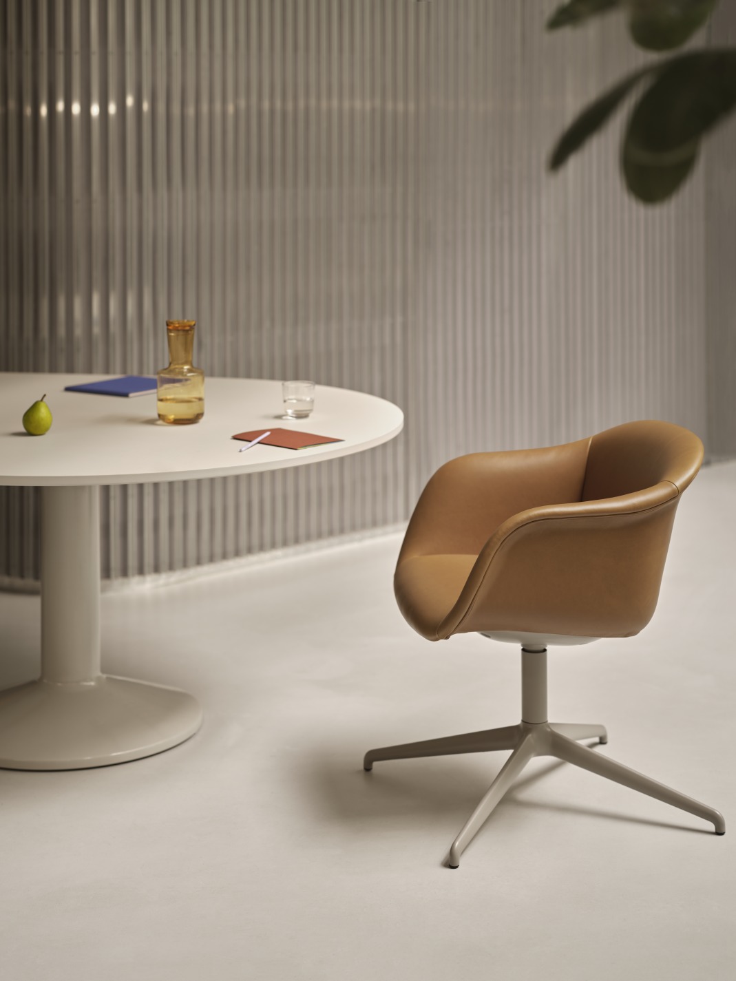 Runder, weißer Konferenztisch von Muuto mit braunem Ledersessel für moderne Büros und Besprechungsräume.
