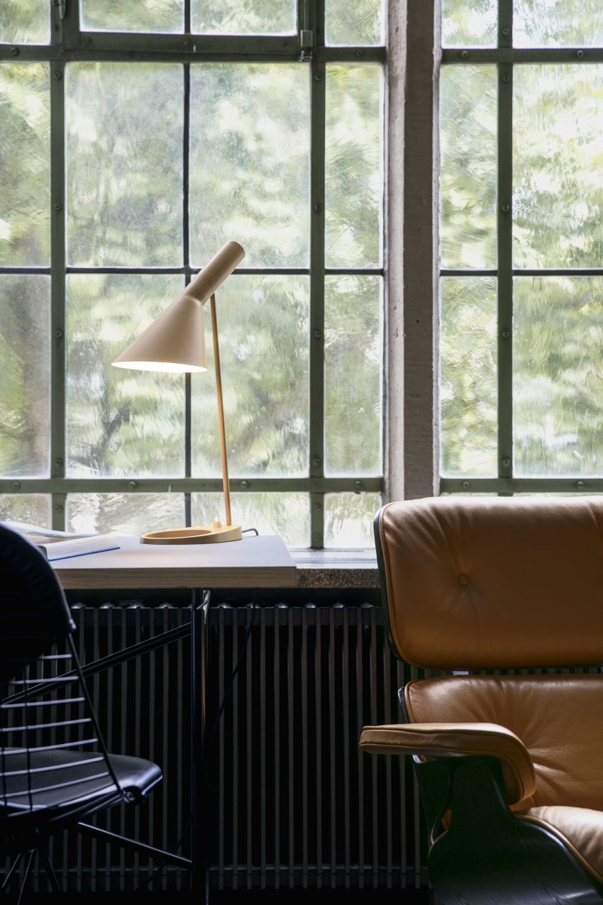 Beige AJ Tischleuchte von Louis Poulsen auf einem Schreibtisch vor einem Fenster. Designklassiker.