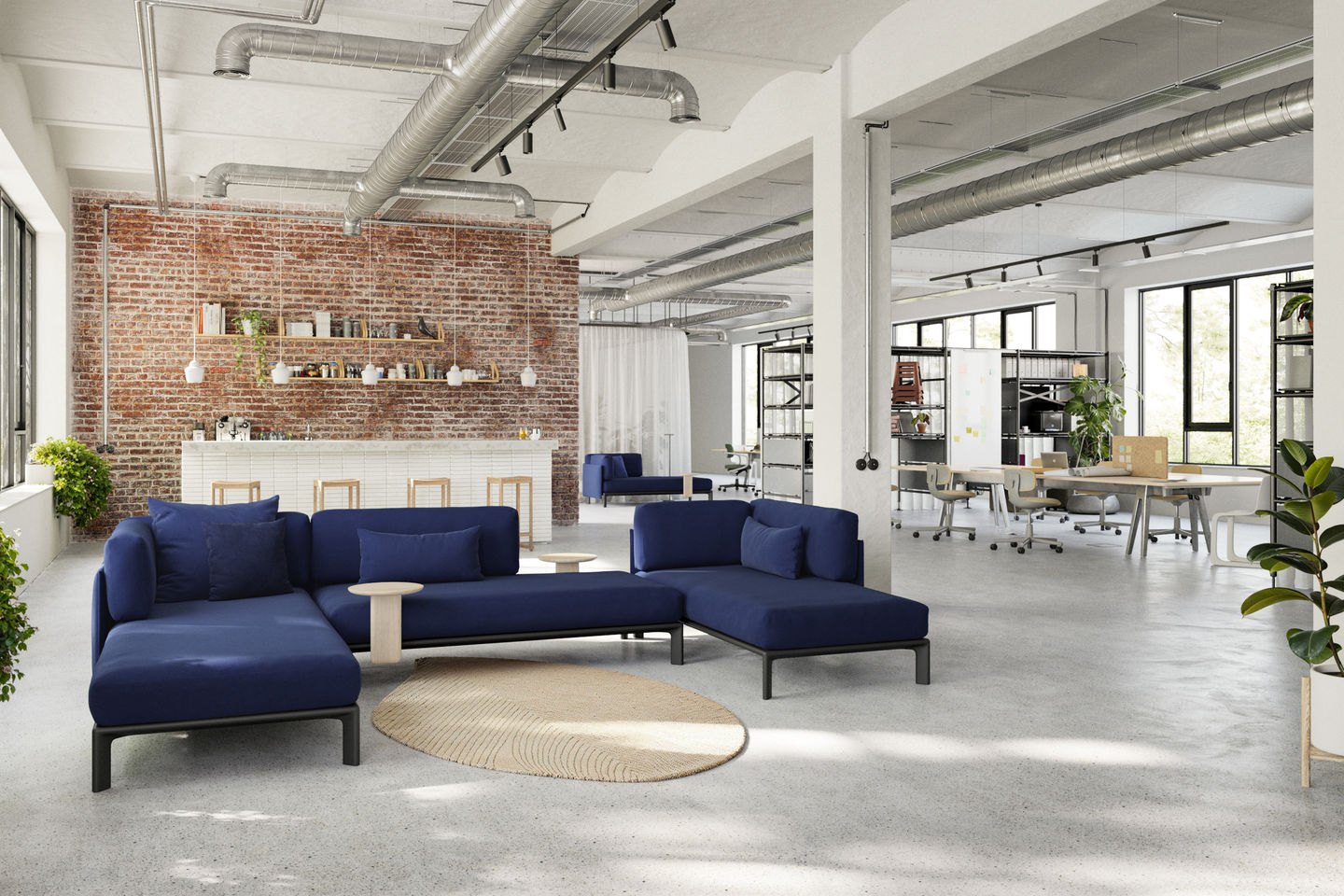 Offene Büroraumgestaltung mit modularem blauen Sofa und Vitra Anagram Plattformverbinder, ideal für flexible Arbeitsbereiche.