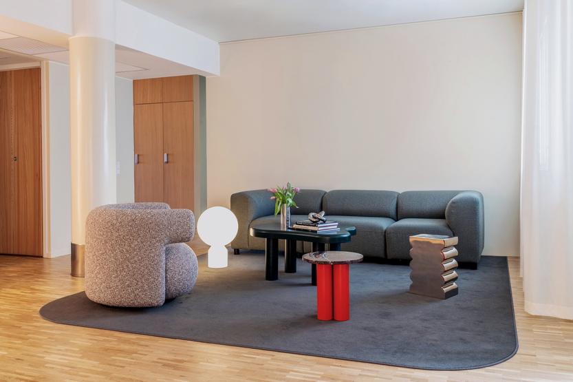 Wohnzimmer mit grauem Sofa, Teppich und mehreren Beistelltischen, darunter ein Dit Coffee Table von Normann Copenhagen.