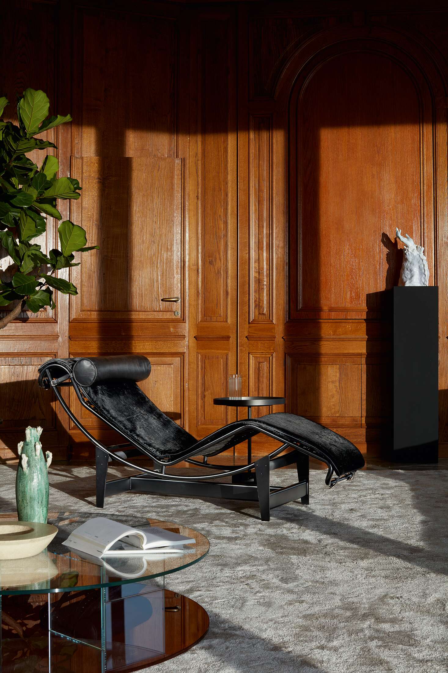 Schwarze Liege LC4 von Cassina mit Lederkopfstütze und Fellbezug in einem eleganten Interieur.