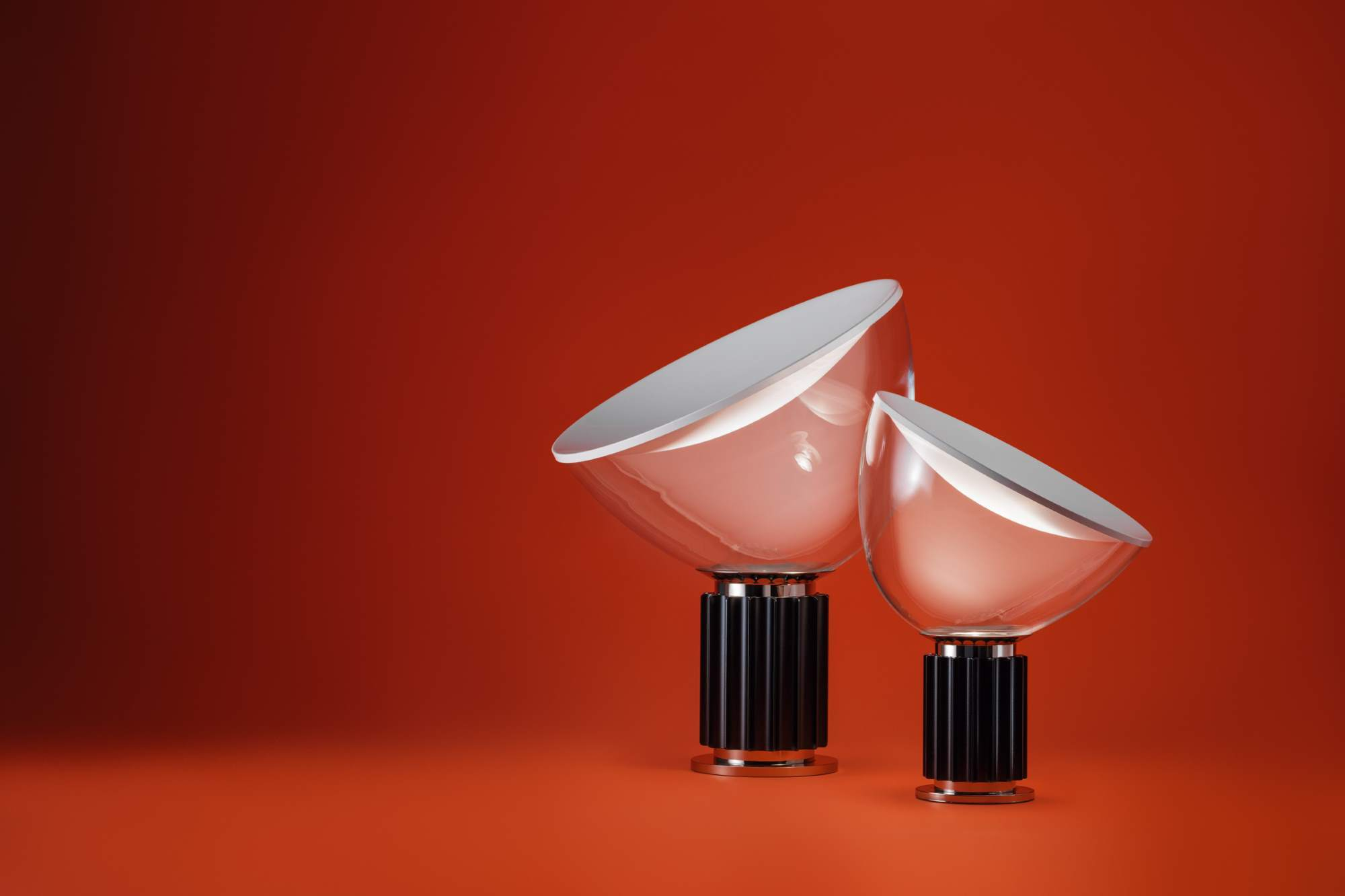 Zwei Taccia Small LED Tischleuchten von Flos in Schwarz vor rotem Hintergrund.