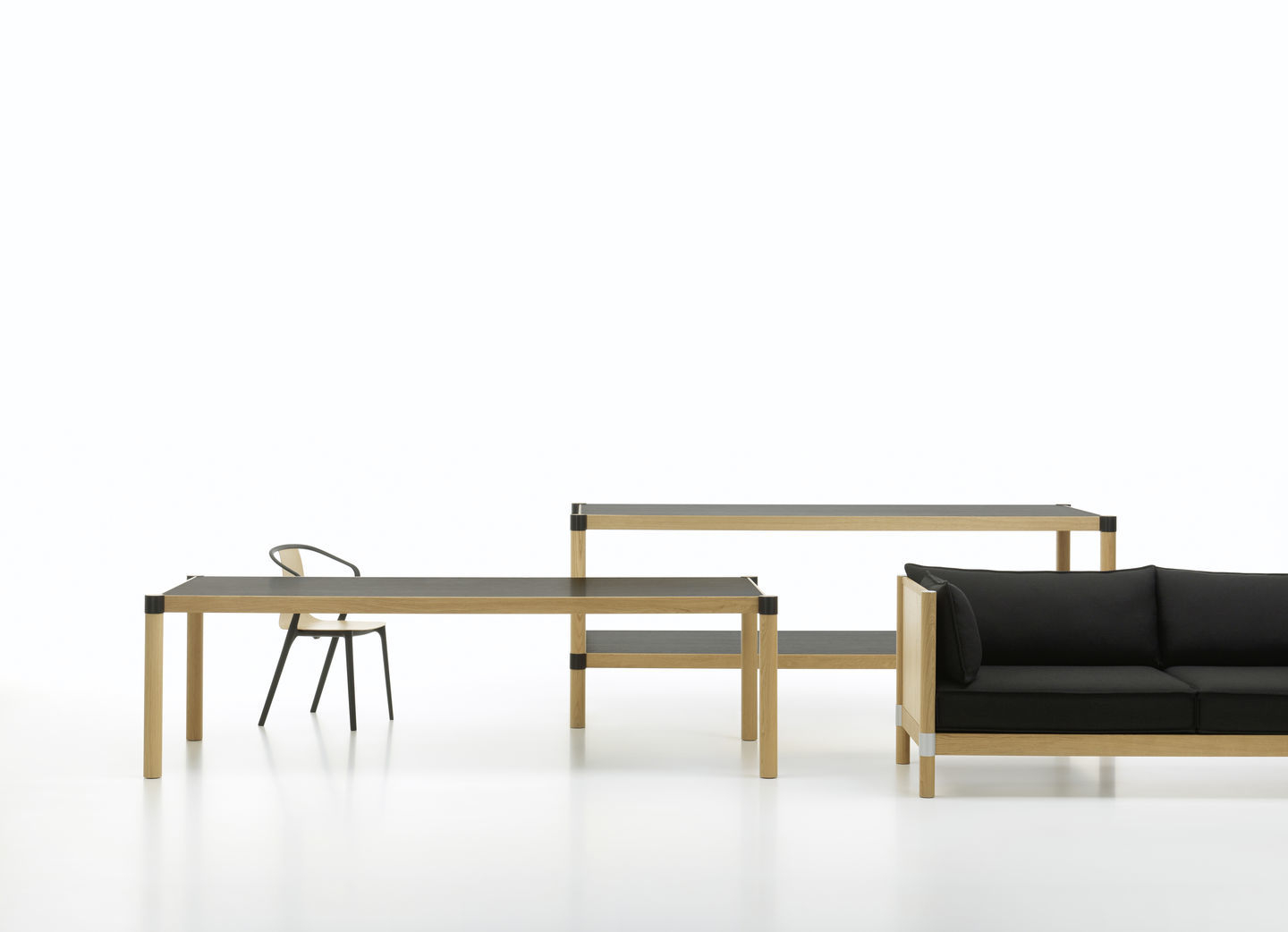 Vitra Belleville Chair Wood Stuhl, Esstisch und Sofa in hellem Holz und Schwarz vor weißem Hintergrund.