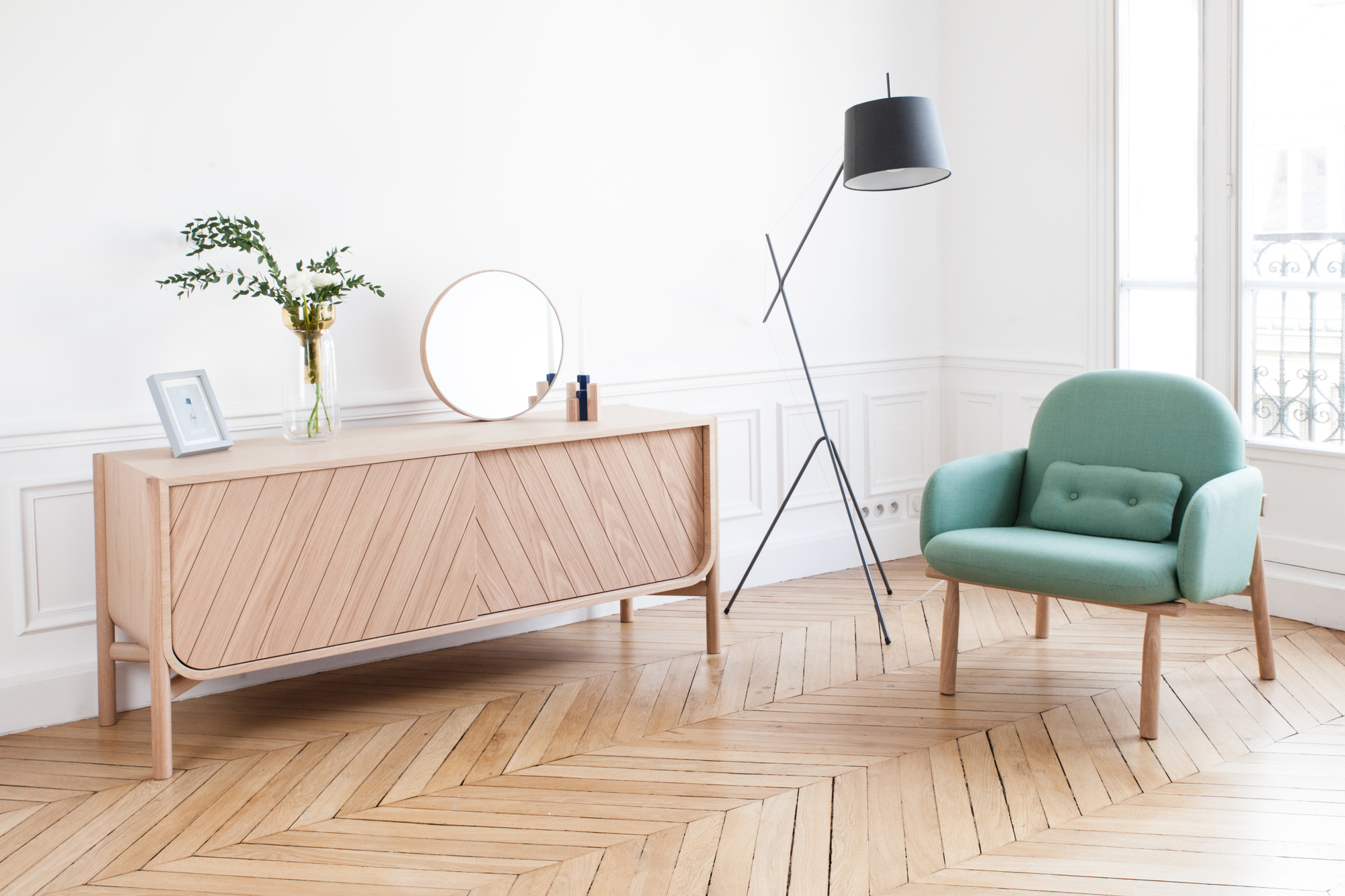 Marius Sideboard von Hartô aus hellem Holz im Wohnzimmer mit Sessel und Lampe.