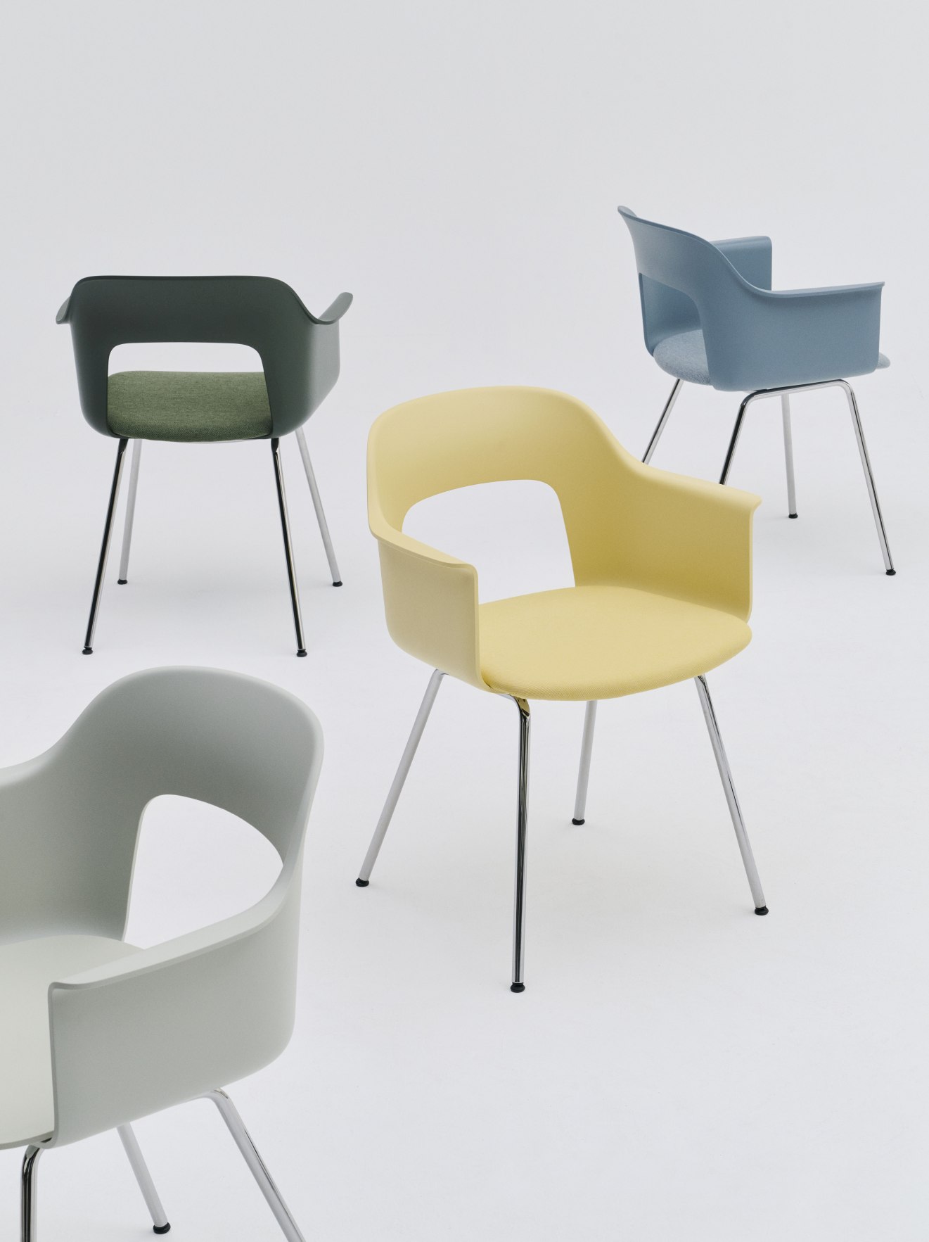 Hay Armlehnstühle Layout Armchair 214 in Gelb, Grau, Grün und Blau mit verchromten Beinen auf weißem Hintergrund.