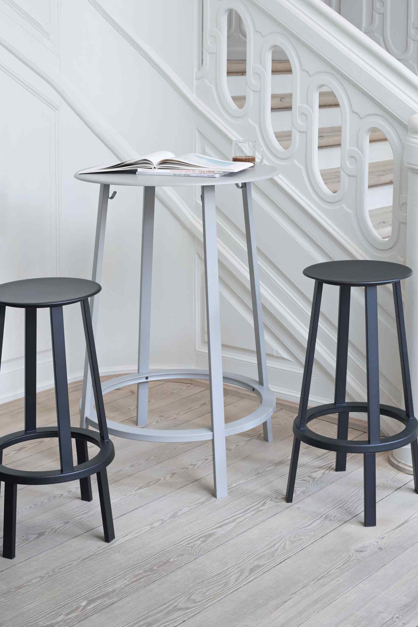 Zwei graue Barhocker und ein Stehtisch von Hay, Modell Revolver Bar Stool High, im Treppenhaus.