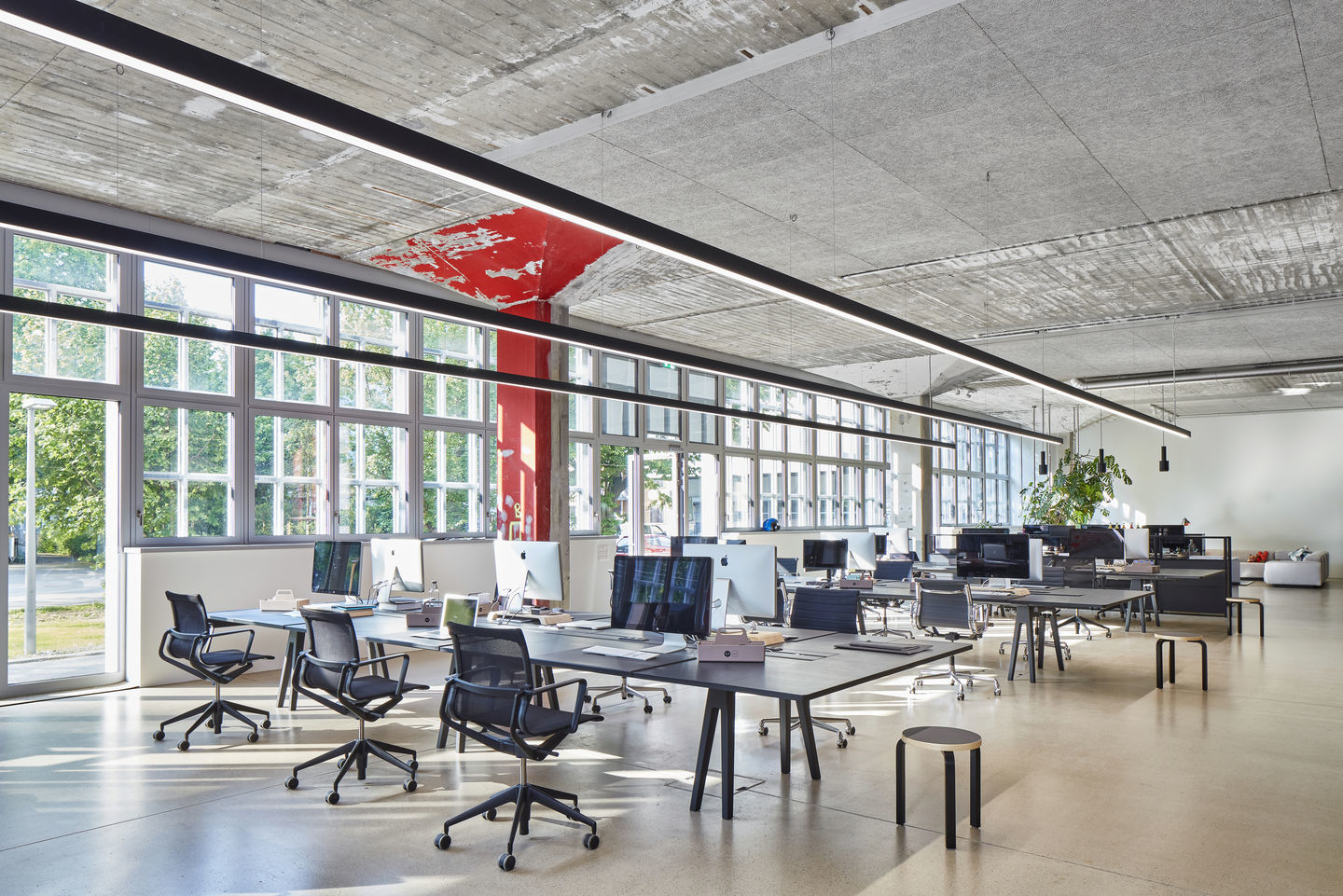Offener Büroraum mit schwarzen Physix Studio Bürodrehstühlen von Vitra an modernen Schreibtischen unter Tageslicht.