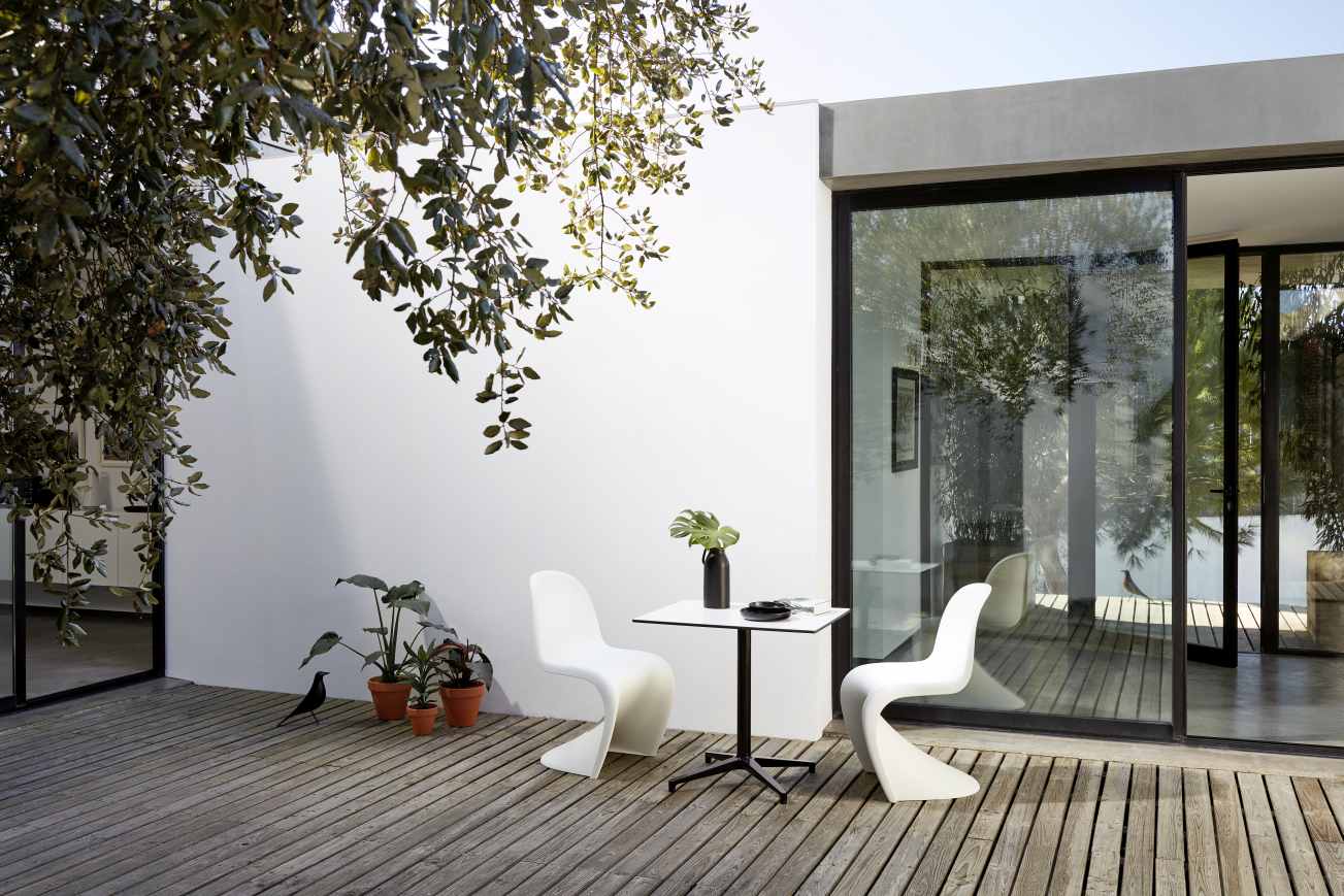 Vitra Bistro Table, rechteckiger Outdoor-Tisch mit zwei weißen Stühlen auf einer Holzterrasse.
