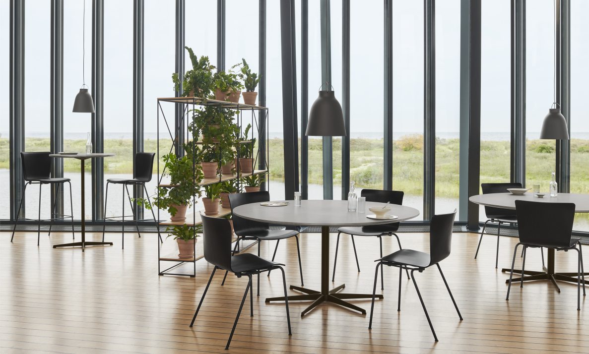 Helle Büroraum-Szene mit Fritz Hansen Caravaggio Pendelleuchten über Tischen und Stühlen, Blick durch Fenster.