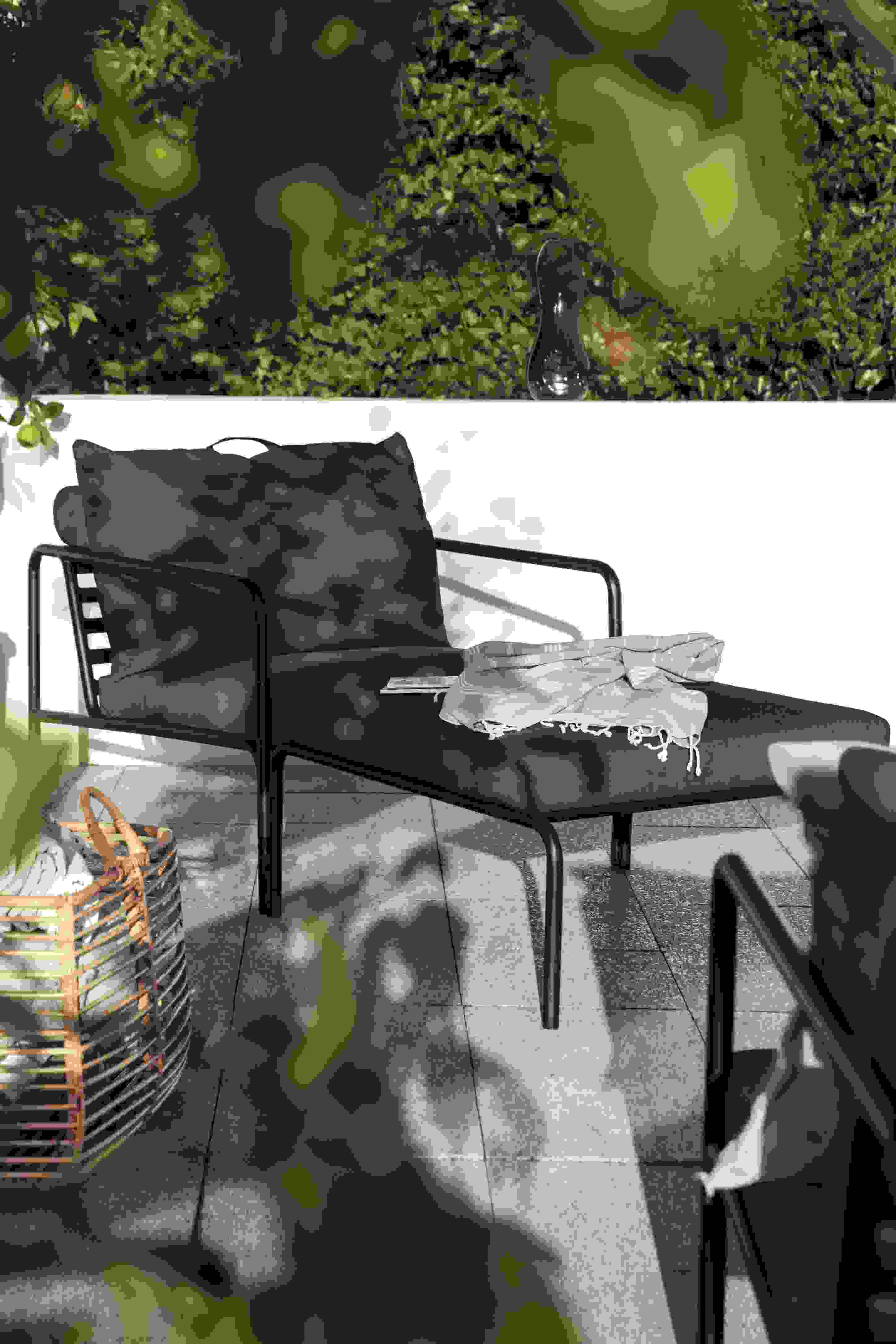 Avon Ottoman Outdoor Hocker mit Kissen und Decke auf einer Terrasse im Garten.