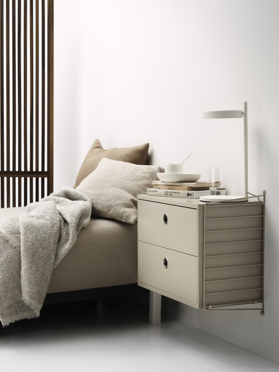 String Nachttisch im Schlafzimmer: Beige Nachttischkommode mit zwei Schubladen und Lampe.