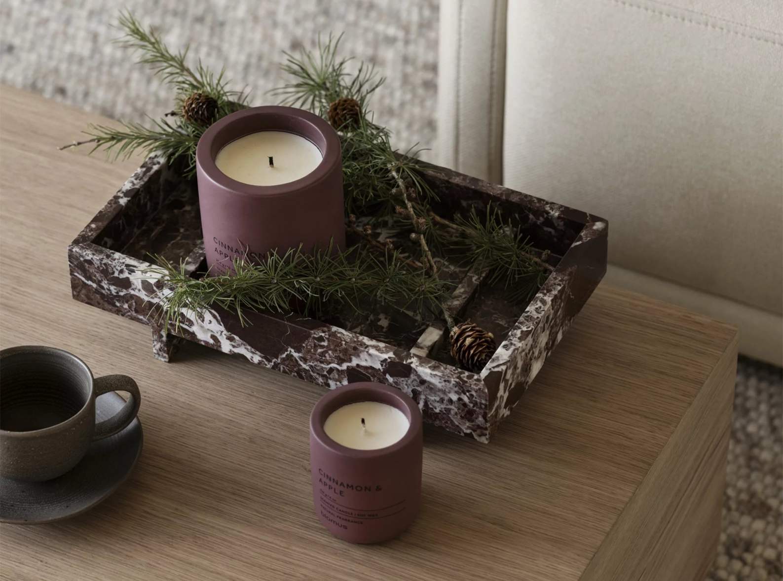 Abento Marmor Tablett von Blomus mit Kerzen und Tannenzweigen auf einem Holztisch.