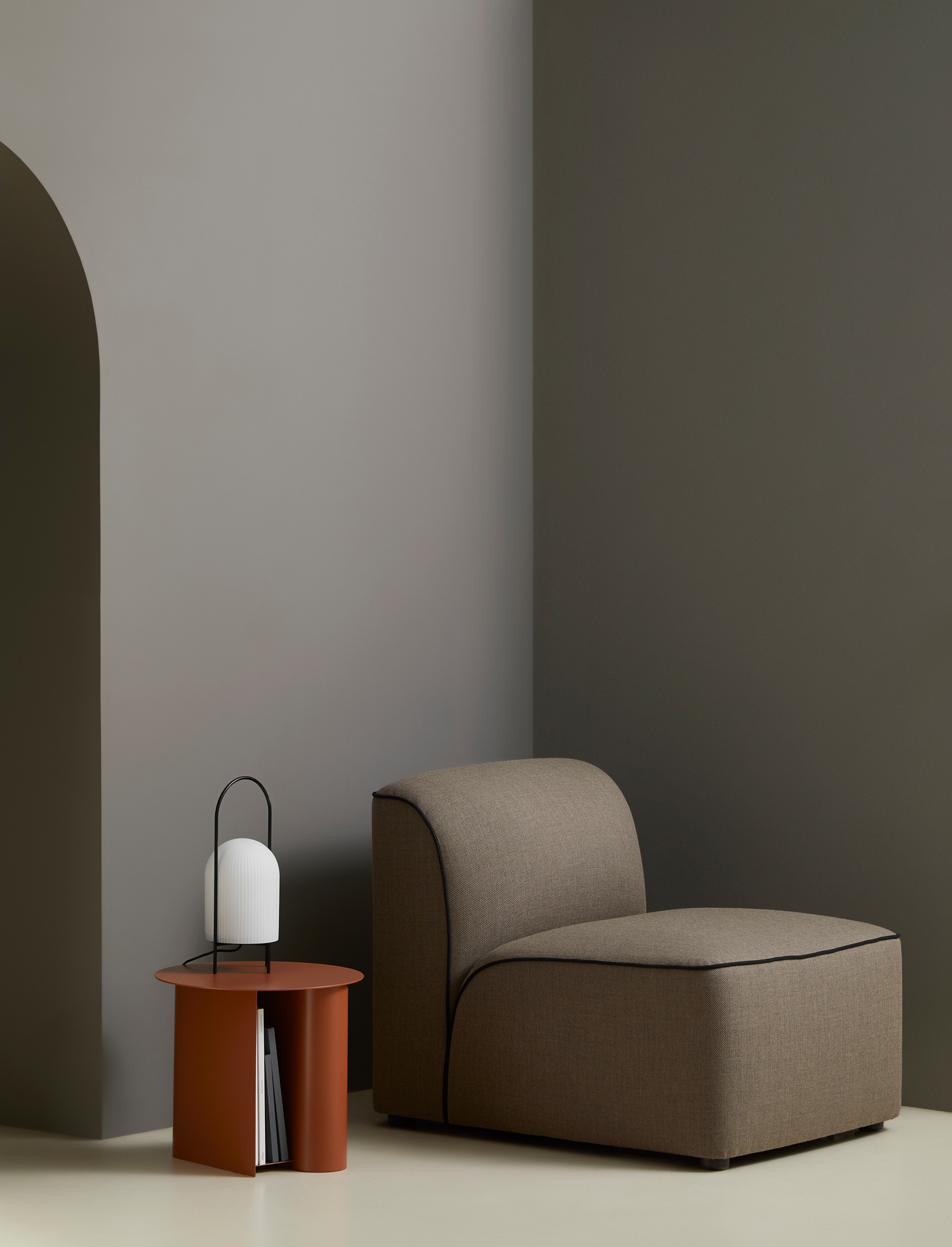 GHOST Tischleuchte von Woud auf orangefarbenem Beistelltisch neben einem braunen Sessel. Moderne Lampe für Wohnzimmer.