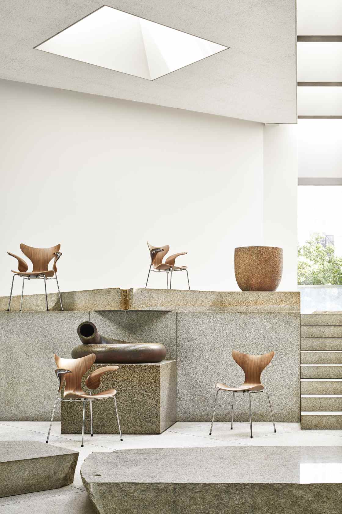 Fritz Hansen Lily Armlehnstuhl 3208 aus Holz und Stahl in modernem Ausstellungsraum.
