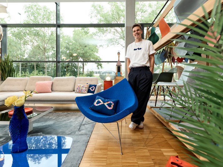 Blauer Vitra Coconut Chair Sessel im modernen Wohnzimmer mit Person und Sofa.