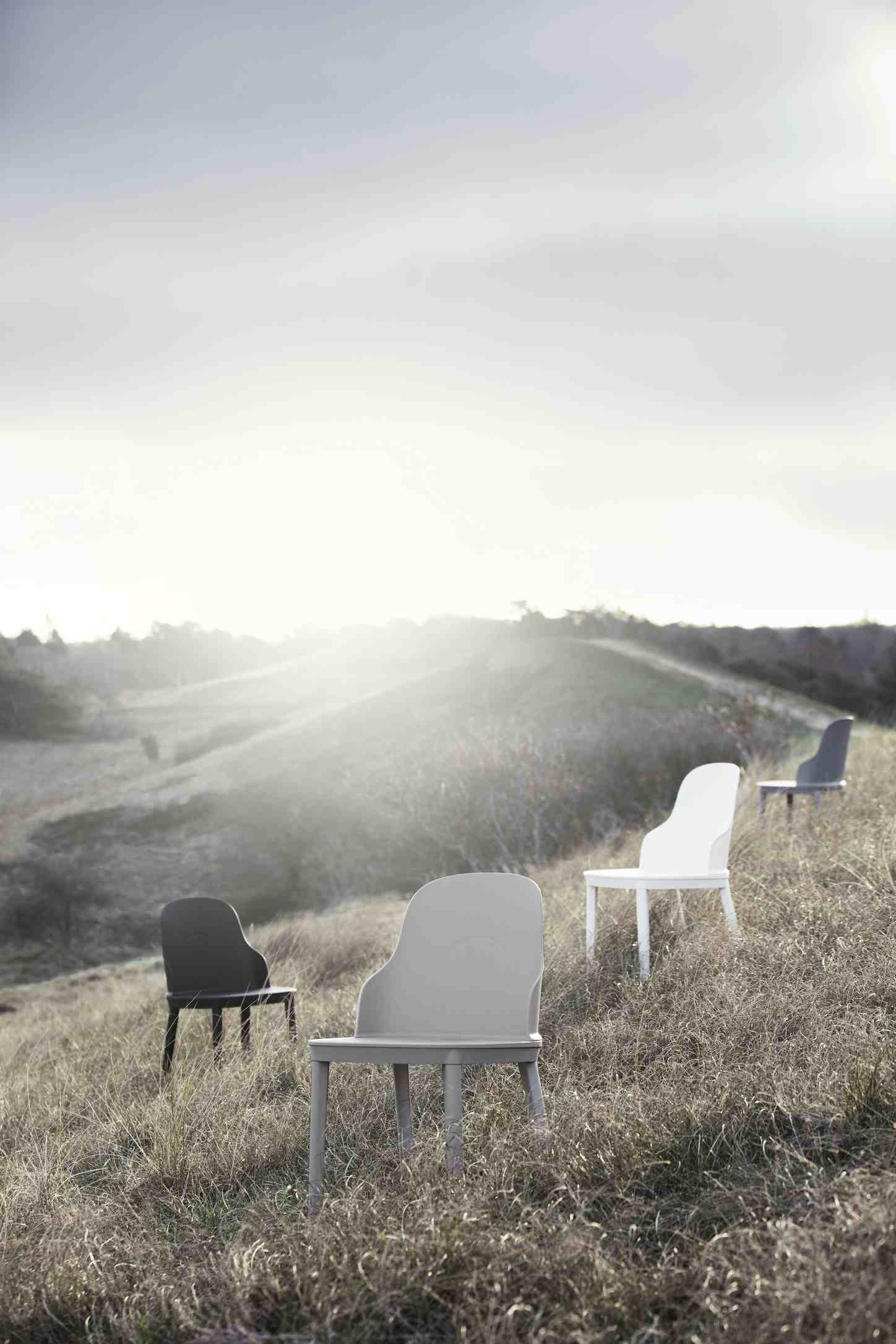 Mehrere Allez Stühle von Normann Copenhagen in verschiedenen Farben auf einer Wiese.