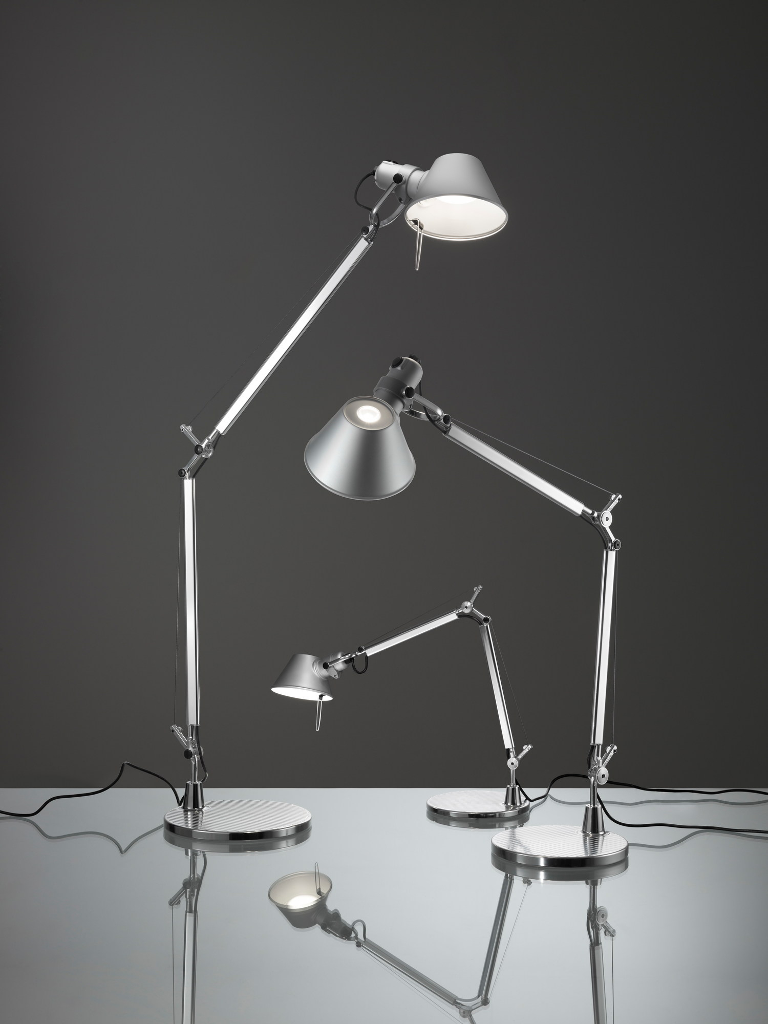 Drei silberne Tolomeo LED Tischleuchten von Artemide mit verstellbaren Armen und Kegelförmigen Lampenschirmen.
