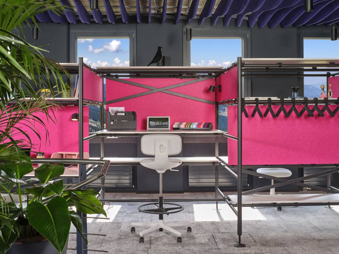 Vitra Rookie High Bürodrehstuhl in weiß vor pinkfarbener Büroeinrichtung mit Schreibtisch und Regalen.
