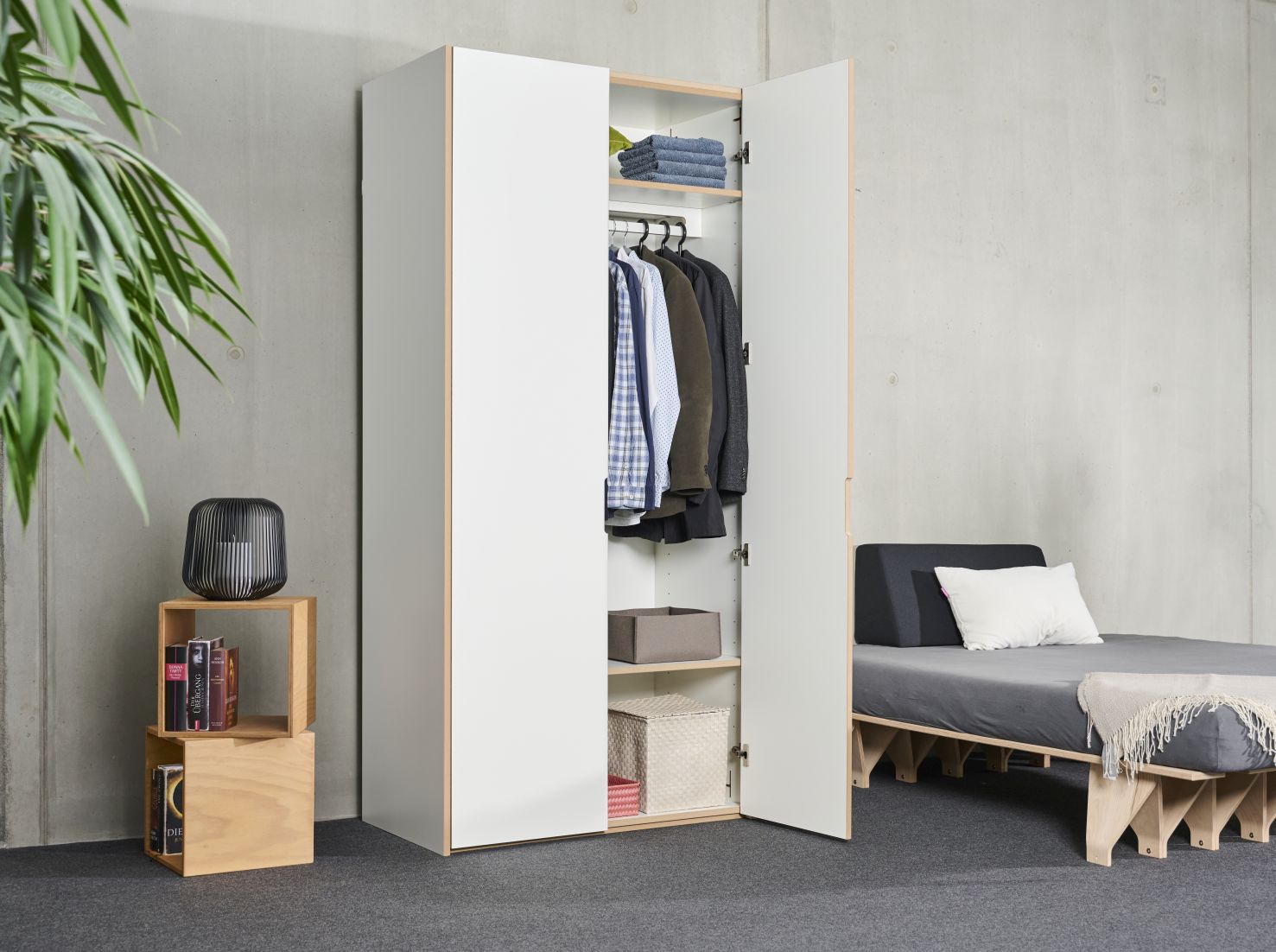 Tojo Schrank Grundmodul, weißer Kleiderschrank mit offener Tür, Innenraum mit Kleidung und Ablagefächern.