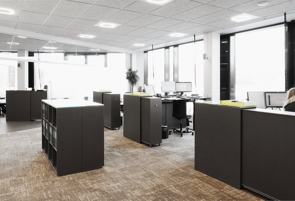 Modernes Büro mit Montana Cargo Modul 80 Schrank-Systemen in Anthrazit, die als Raumteiler und Stauraum dienen.