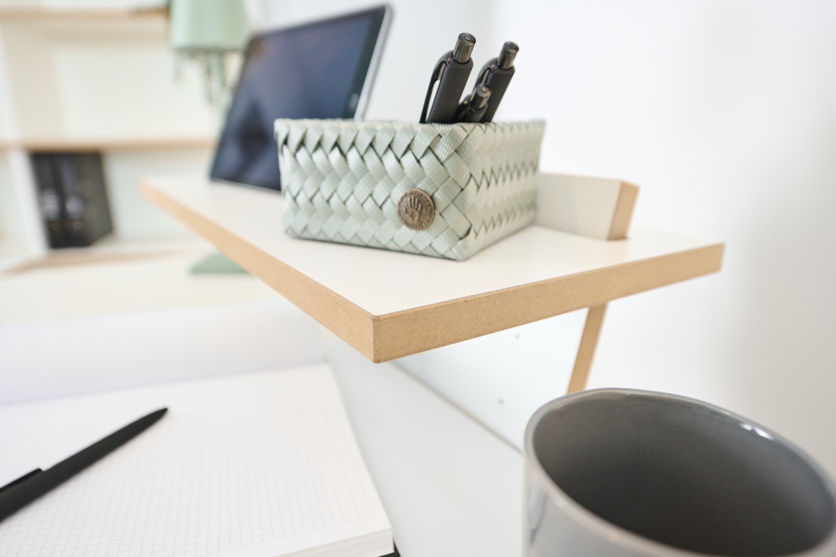 Detailaufnahme vom Tojo Stehpult mit Schreibtisch-Utensilien wie Stifthalter, Stifte, Notizbuch und Becher.