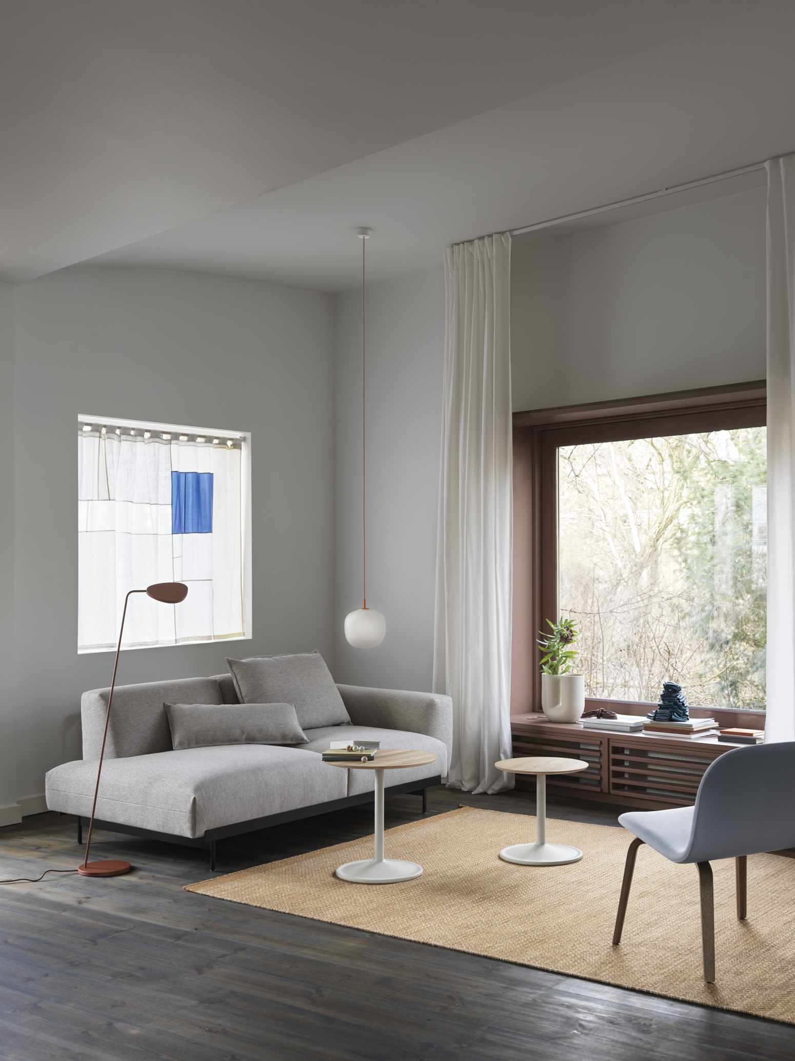Helles Wohnzimmer mit grauem Sofa und zwei Muuto Soft Side Table Beistelltischen auf einem Teppich.