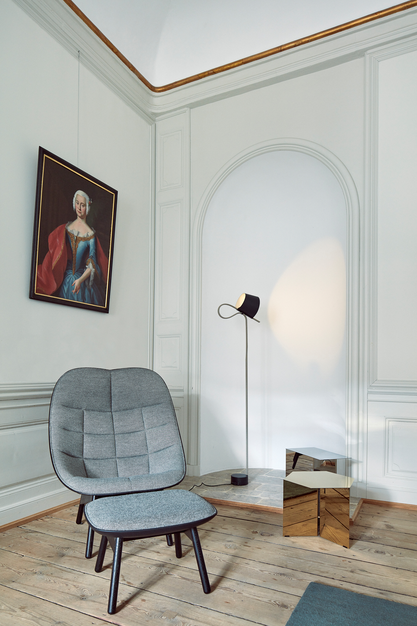 Grauer Uchiwa Quilt Sessel von Hay mit Fußhocker in stilvollem Interieur mit Lampe und Gemälde.
