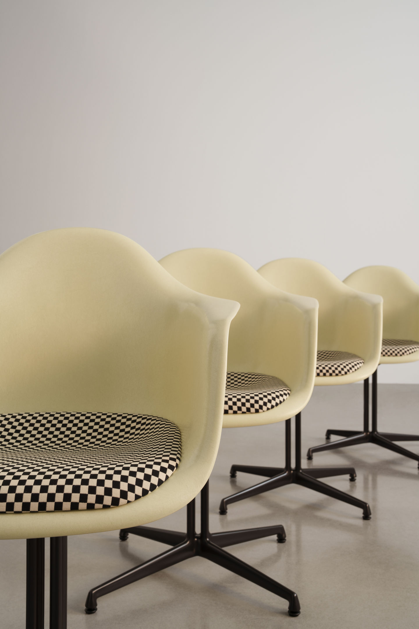 Reihe von Eames Plastic Arm Chairs DAL von Vitra mit Schachbrettmuster-Sitzpolster und schwarzem Untergestell.