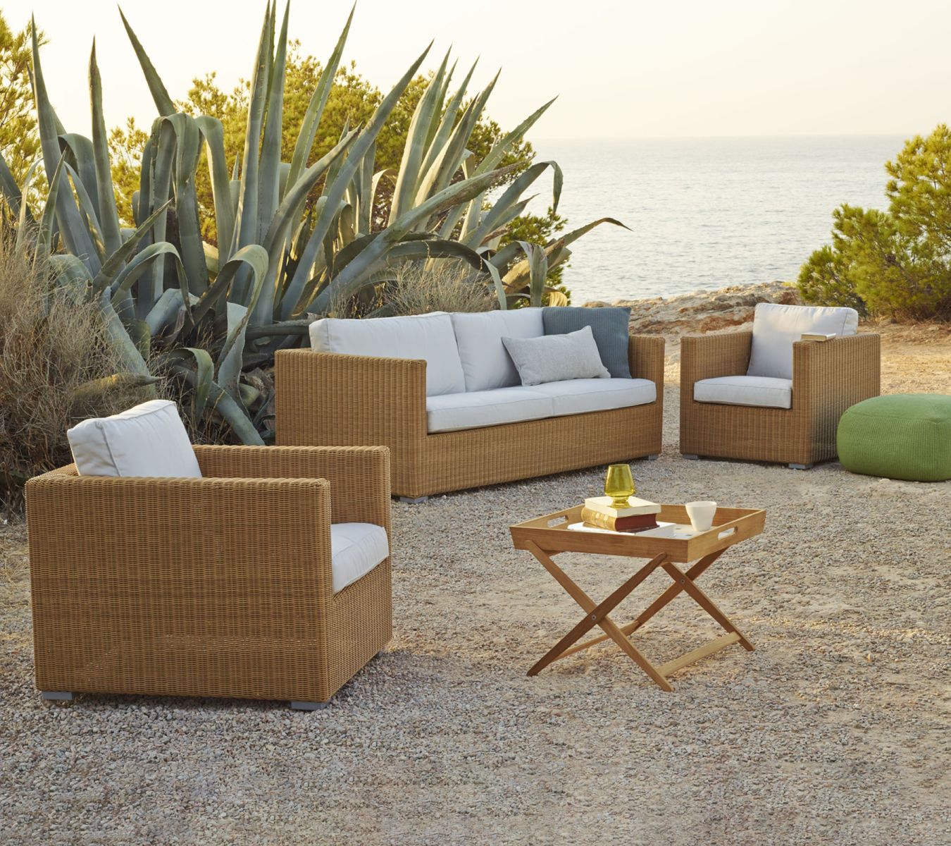 Chester 3-Sitzer Sofa von Cane-Line: Gartenmöbel-Set aus Rattan mit weißen Kissen im Freien.