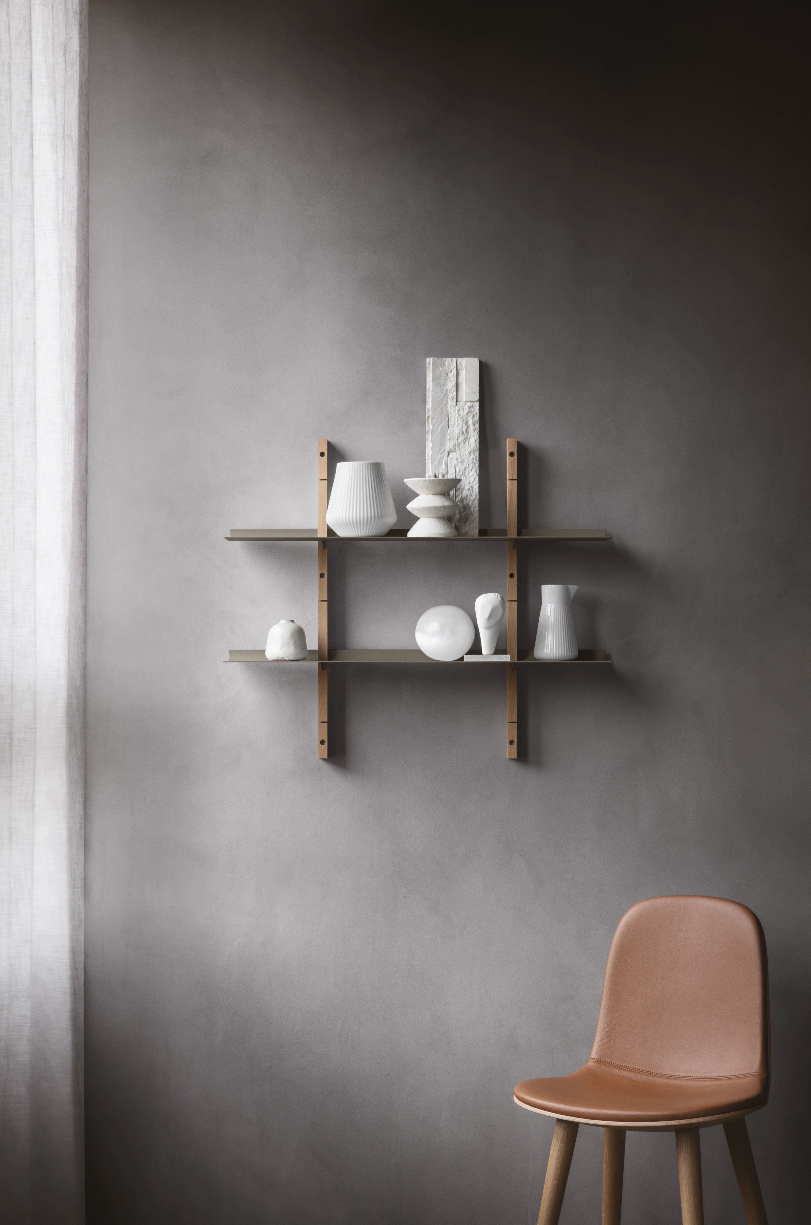 EVA SOLO Abalone Stuhl aus Eiche mit braunem Ledersitz vor grauer Wand. Design Stuhl.