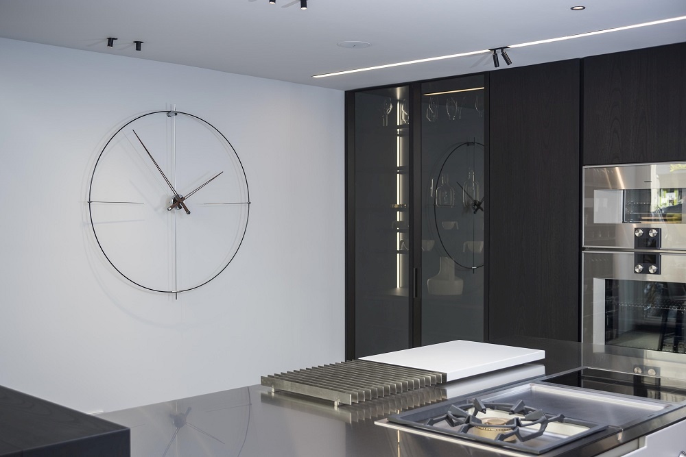 Weiße Nomon Wanduhr Bilbao N/L an einer Wand in einer modernen Küche.