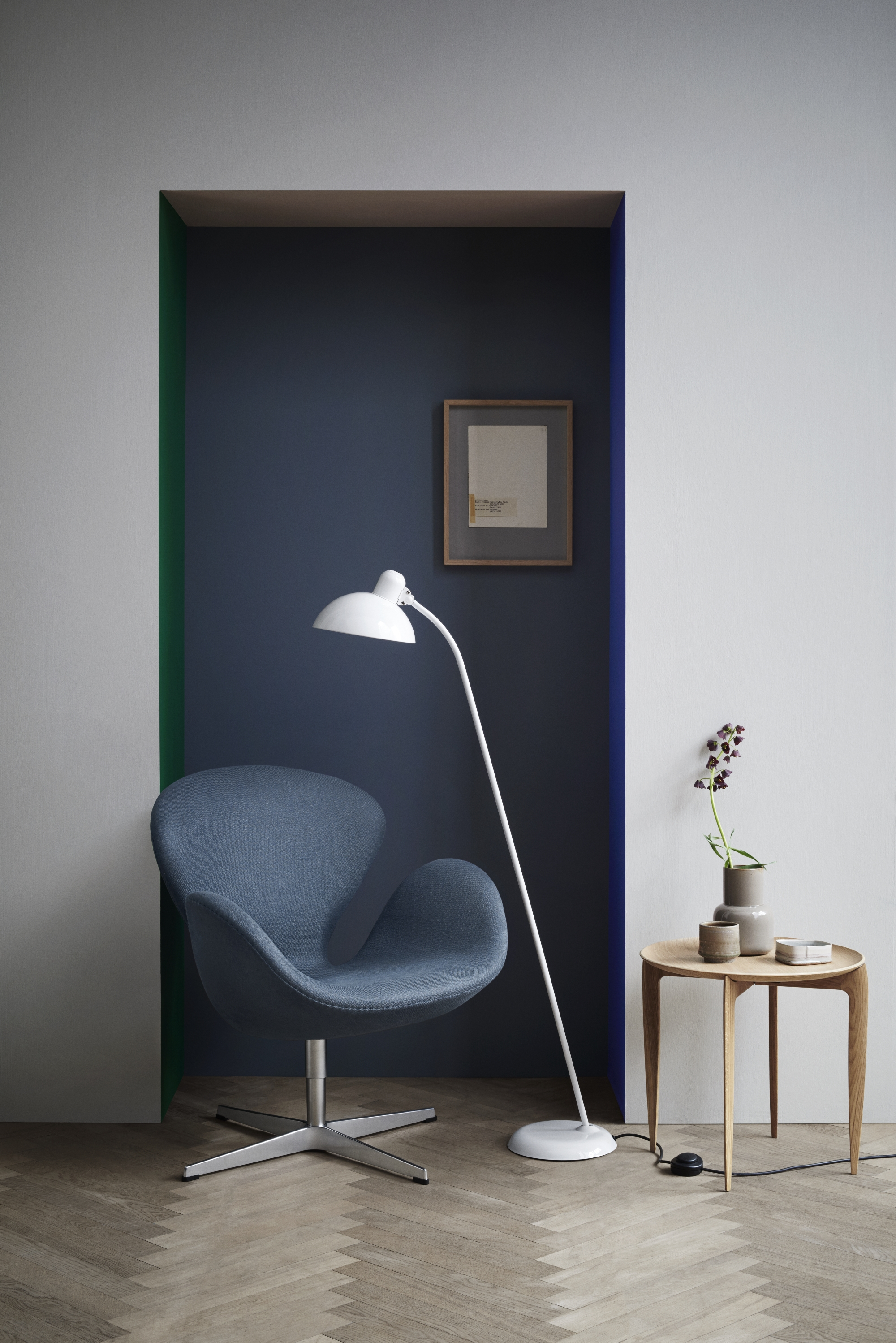 Blauer Swan Sessel von Fritz Hansen mit weißer Stehlampe und Holztisch in modernem Interieur.