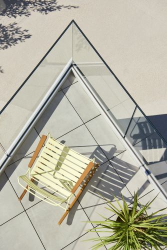 Draufsicht: Gelber Fermob Surprising Schaukelstuhl auf Terrasse mit Glasgeländer, Outdoor-Möbel für Garten und Balkon.