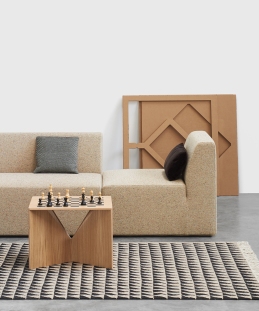 Beiges Kerman Modulsofa von e15 mit Schachbrett-Tisch und gemustertem Teppich in modernem Wohnzimmer.