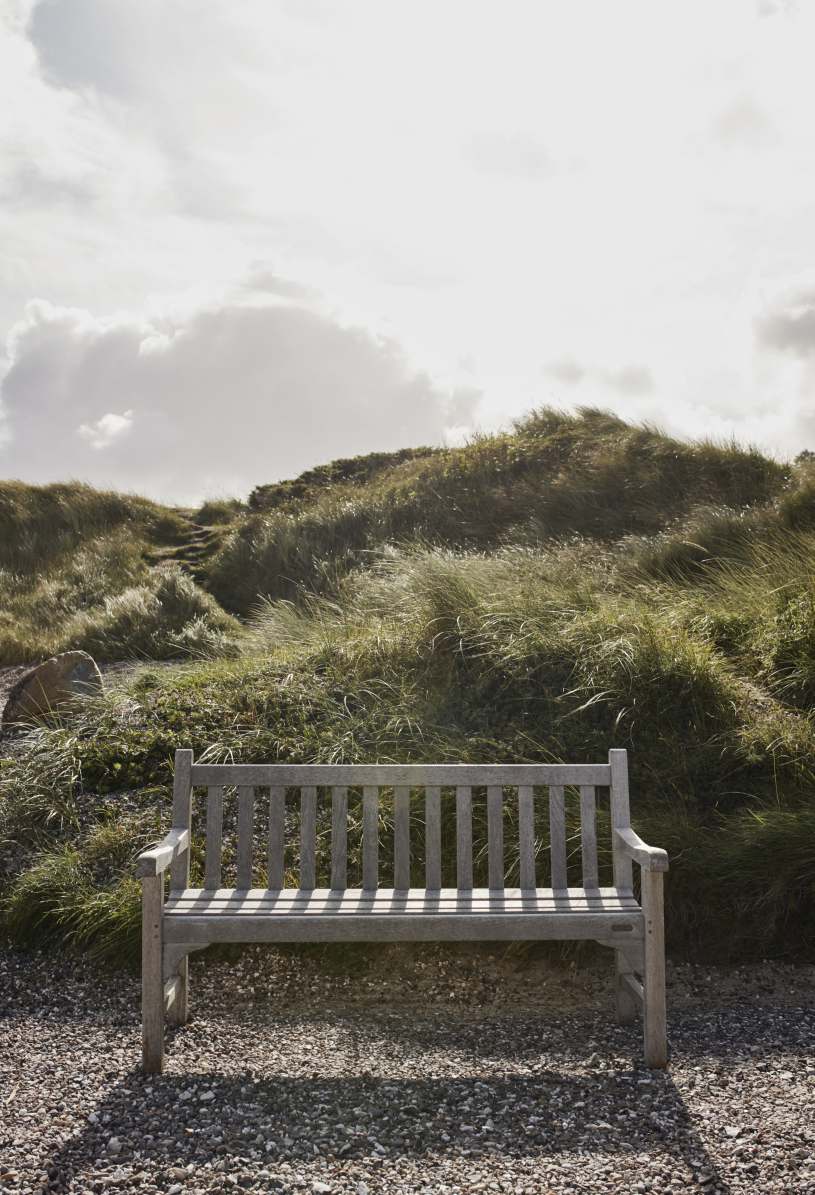 Skagerak England Bank aus Teakholz im Freien vor Dünenlandschaft. Gartenbank für Terrasse.