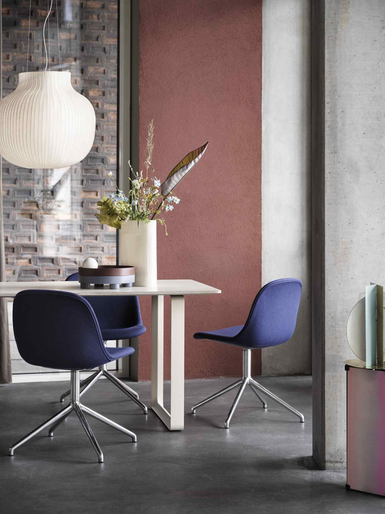 Muuto Strand Pendelleuchte über Esstisch mit blauen Stühlen in modernem Esszimmer.