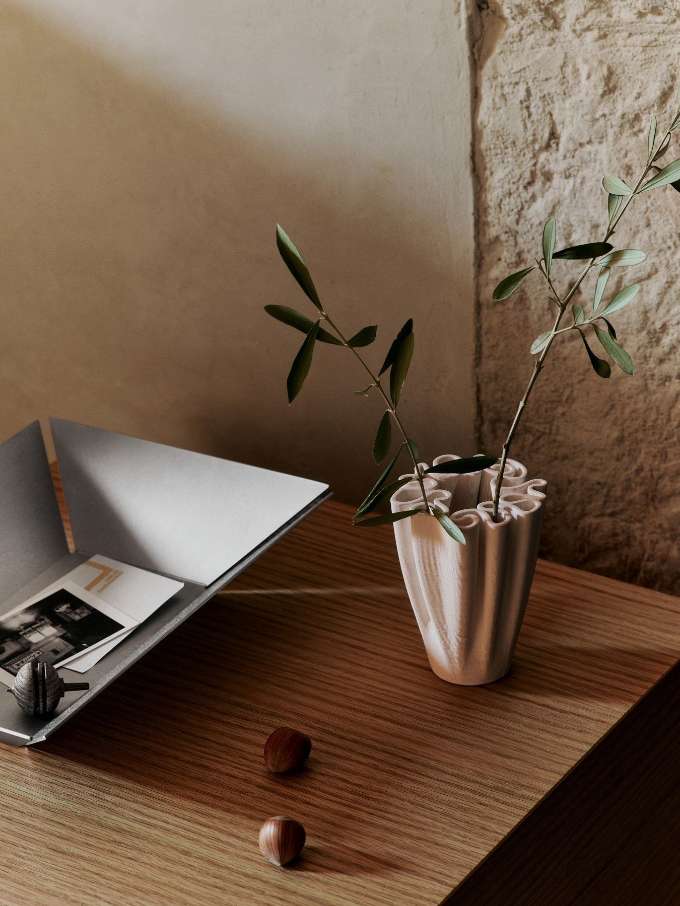 Nahaufnahme der Ferm Living Dedali Vase Medium in Off-White mit Olivenzweig auf einem Holztisch.