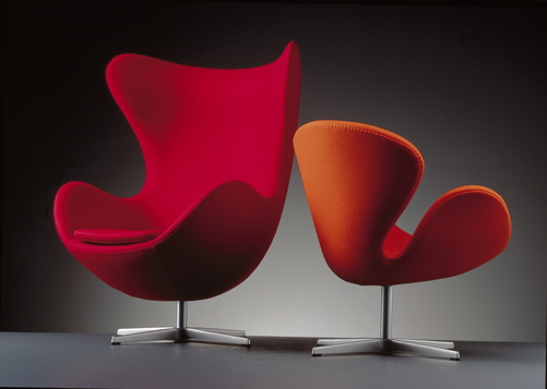 Zwei Design-Sessel: Roter Egg Chair und oranger Schwan Sessel von Fritz Hansen auf Dreifuß.