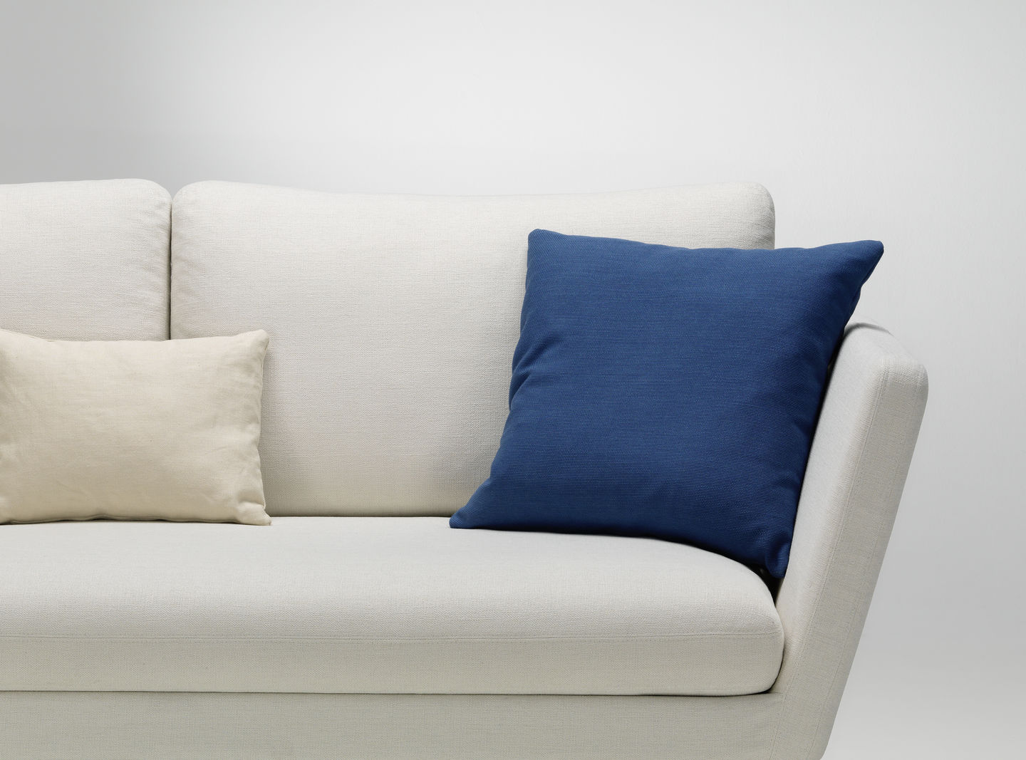 Vitra Kissen: Beige und blaues Sofakissen auf einem hellen Sofa, Dekokissen für Wohnzimmer.