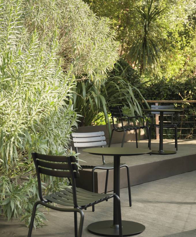 Alua Dining Chair von Houe, ein moderner Outdoor-Stuhl aus Metall in einer grünen Gartenszene.