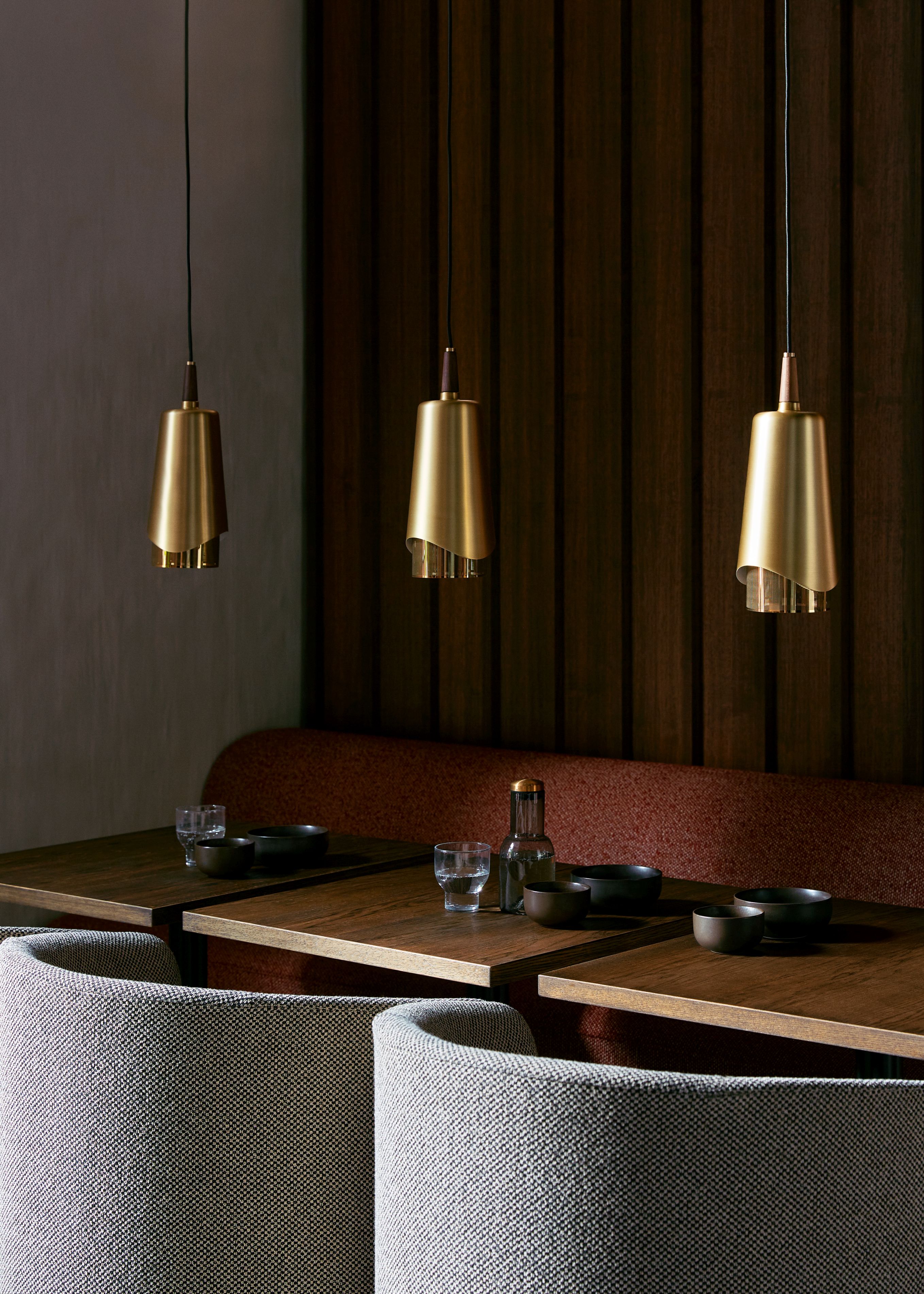 Drei goldene Umanoff Hängeleuchten von Audo über Esstischen in einem Restaurant, moderne Innenarchitektur.