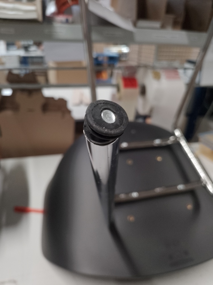 Detailaufnahme vom Fuß eines schwarzen About A Chair AAC26 Stuhls mit Chromgestell, Fokus auf den Bodengleiter.